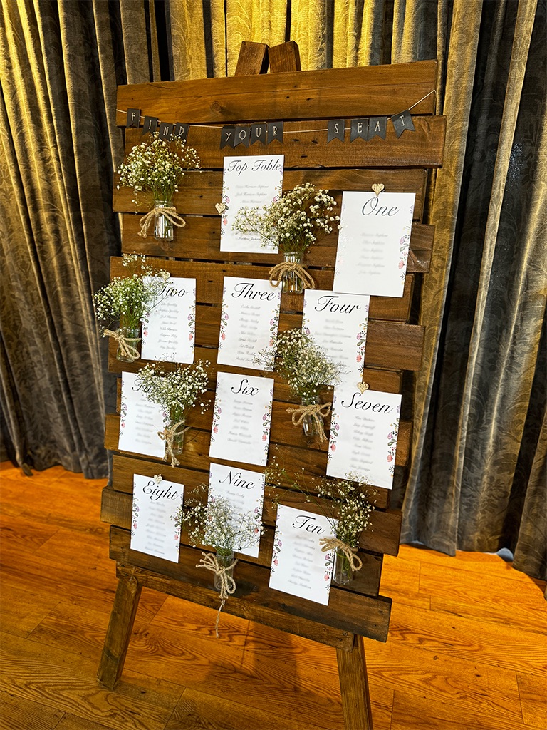 Wooden wedding table plan with easel and glass jars